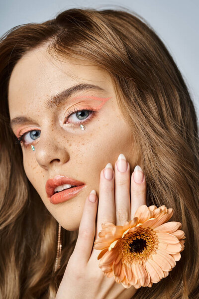Крупный план красоты женщина подмигивает персиковый макияж, gerbera ромашки, лица драгоценности и веснушки