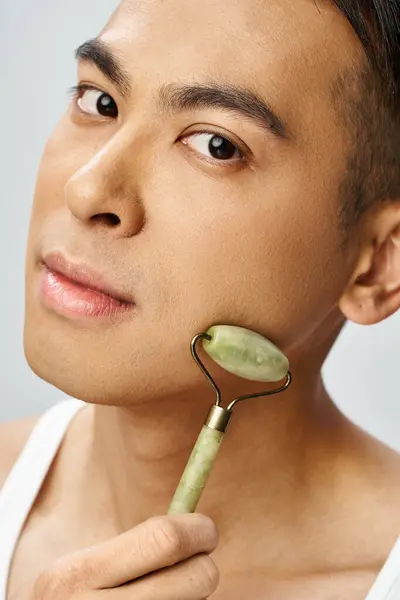 Handsome Asian Man Holding Jade Roller His Face Grey Studio — Stock Photo, Image