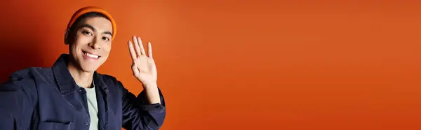 Стильный Азиат Синей Куртке Жестикулирует Рукой Ярком Оранжевом Фоне Студии — стоковое фото