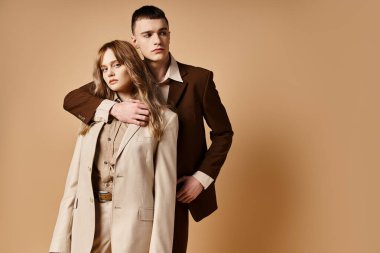 Sofistike, güler yüzlü bir adam kameraya bakan güzel kız arkadaşının yanında poz veriyor.