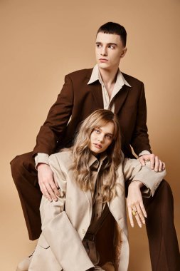 appealing young woman in pastel suit looking at camera sitting next to her handsome boyfriend clipart