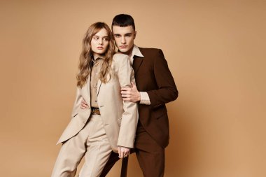 elegant man in suit posing with his beautiful girlfriend and looking at camera on pastel backdrop clipart