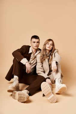 Şık takım elbiseli güzel bir kadın güzel sevgilisinin yanında poz veriyor ve kameraya bakıyor.