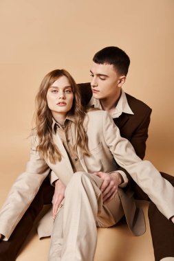 Şık takım elbiseli güzel bir kadın güzel sevgilisinin yanında poz veriyor ve kameraya bakıyor.