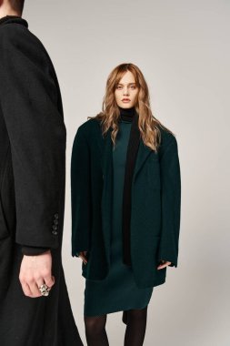 Güzel görünümlü moda erkek arkadaşı ve kız arkadaşı gri arka planda sevgiyle poz veriyorlar.