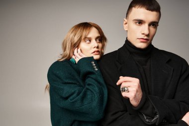 Gri arka planda gri önlüklü güzel güler yüzlü çift başka tarafa bakıyor.