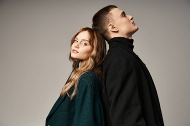 Ceketli şık bir adam kameraya bakan güzel kız arkadaşının yanında sevgiyle poz veriyor.