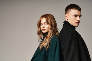 Ceketli şık bir adam kameraya bakan güzel kız arkadaşının yanında sevgiyle poz veriyor.