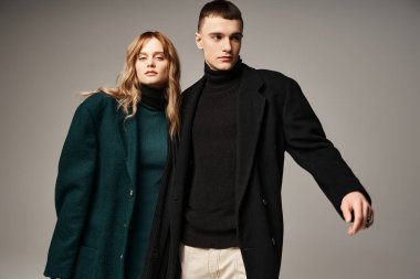 Ceketli yakışıklı adam kameraya bakan güzel kız arkadaşının yanında sevgiyle poz veriyor.