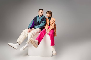 Canlı moda bombardıman uçakları içinde, beyaz küpte mutlu mesut birbirlerine bakan neşeli bir çift.