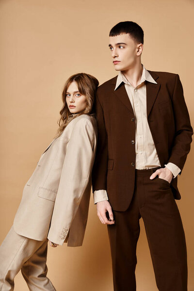 young handsome man in debonair suit posing next to his beautiful girlfriend who looking at camera