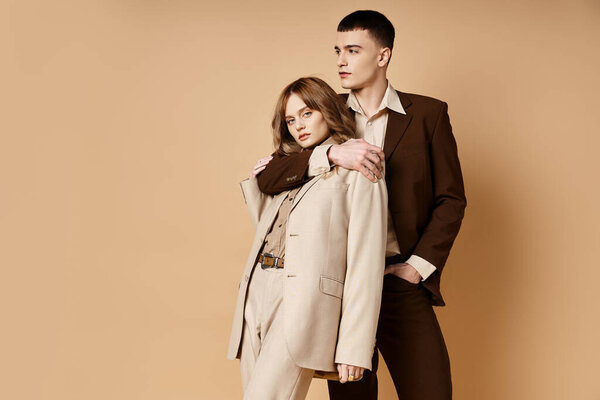 elegant handsome man in debonair suit posing next to his beautiful girlfriend who looking at camera