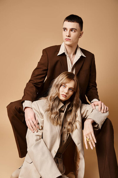 appealing young woman in pastel suit looking at camera sitting next to her handsome boyfriend