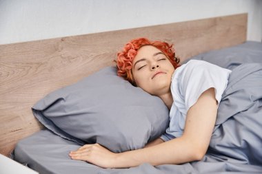 good looking red haired queer person in cozy homewear napping in her bed at home, leisure time clipart