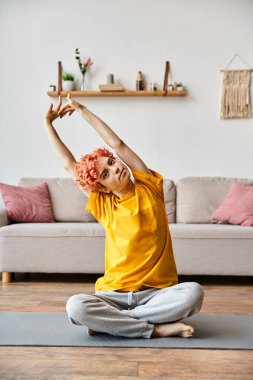 Canlı spor giyimli, kızıl saçlı, kaslarını esneten ve kameraya bakan tuhaf bir adam.