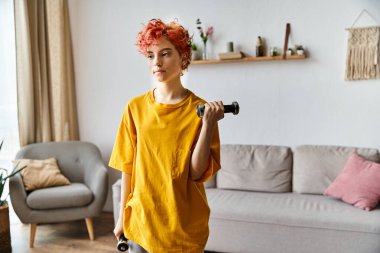 Canlı spor kıyafetleri içinde çekici, genç bir homo evde halterlerle egzersiz yapıyor.