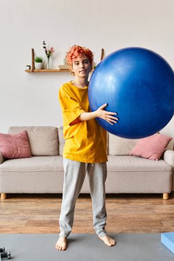 Keyifli, müsrif, rahat giysiler içinde spor salonunda spor yapıyor ve kameraya gülümsüyor.