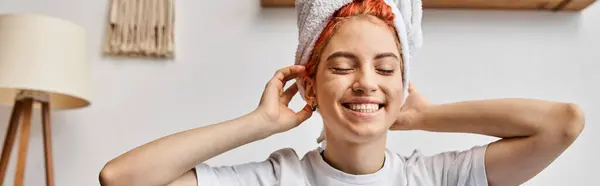 stock image cheerful extravagant person with hair towel sitting on her bed at home, morning routine, banner