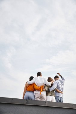 Çatıda poz veren sıradan şehir kıyafetleri içindeki bir grup genç çok kültürlü arkadaşın arka plan görüntüsü