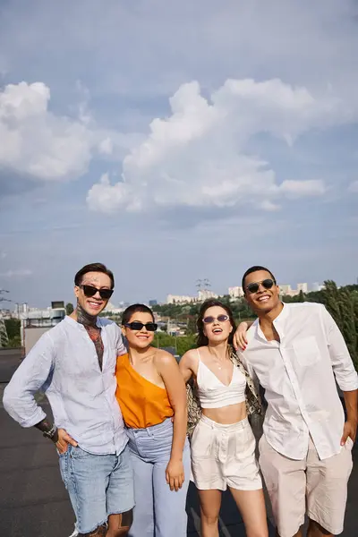 group of interracial joyous friends with modern sunglasses posing happily on rooftop together