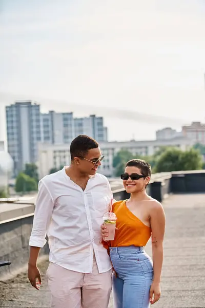 stock image joyous interracial friends with sunglasses in vibrant attires drinking and partying on rooftop