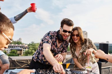 Moda güneş gözlüklü neşeli çok ırklı arkadaşlar DJ 'le çatıdaki partide harika vakit geçiriyorlar.