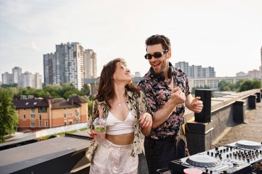 Neşeli, güzel bir kadın, güzel bir DJ ile kokteyl dansı yapıyor çatıdaki partide müzik eşliğinde.