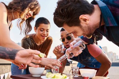 Canlı giysiler içinde ırklar arası neşeli arkadaşlar partide tuzlu ve limonlu tekila içmeye hazırlanıyorlar.