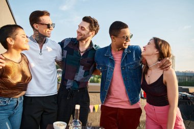 Güneş gözlüklü neşeli arkadaşlar birlikte poz veriyorlar ve partide birbirlerine bakıyorlar.