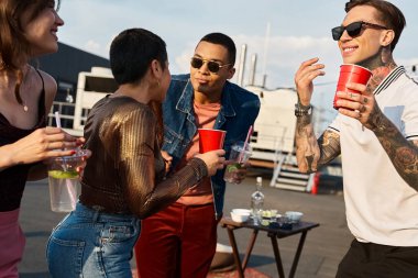 Şehir kıyafetleri içinde güneş gözlüklü, kokteyl içen ve partide eğlenen çok çeşitli arkadaşlar.