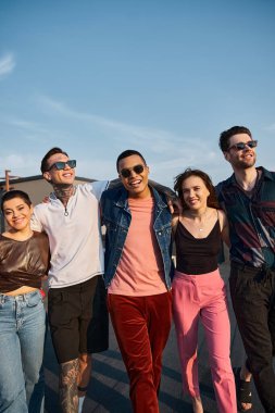 Şık güneş gözlüklü, şehir kıyafetli neşeli çok kültürlü insanlar kameraya gülümsüyor ve eğleniyorlar.