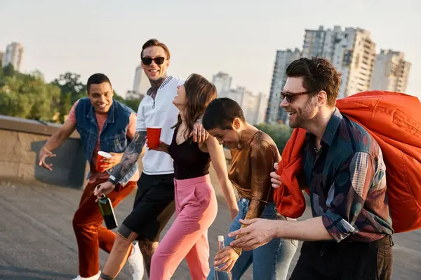 Stock image jolly multicultural friends with different drinks and bean bag chair in hands at rooftop party