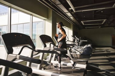 Modern bir spor salonundaki koşu bandında koşan aktif giyimli bir atletik..