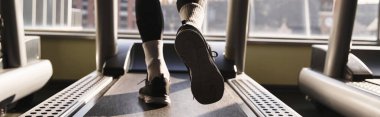 Atletik bir adam spor salonunda koşu bandında yürüyor..