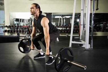 Aktif giyinen atletik bir adam spor salonunda halter kaldırıyor. Güç ve kararlılık gösteriyor..