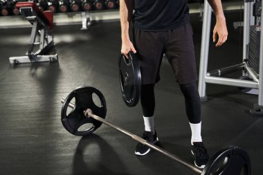 Spor salonunda, halterin yanında. Yoğun antrenman sırasında güç ve kararlılık gösteriyor..
