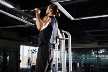 Aktif kıyafetli bir sporcu spor salonundaki barfiks barında egzersiz yapıyor..