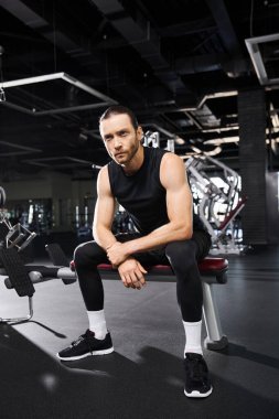 Atletik bir adam spor salonunda otururken spor yaparken biraz dinleniyor..