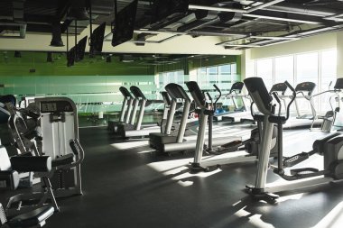 a lineup of exercise machines in an active gym clipart