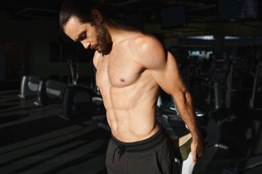Gömleği olmayan kaslı bir adam spor salonunda yoğun bir şekilde çalışıyor, gücünü ve bağlılığını gösteriyor..