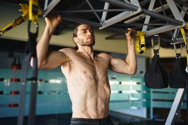 Gömleksiz kaslı adam spor aletlerini kavrayıp, güç ve spor yapmaya odaklanıyor..