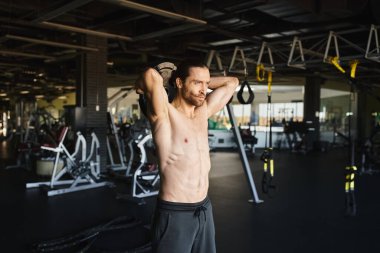 Tişörtsüz kaslı bir adam spor salonunda çalışıyor..