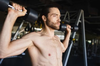 Gömleksiz bir adam kendini limitlerine kadar zorluyor, spor salonunda dambıllar tutuyor..