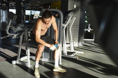 Spor salonunda oturan kaslı adam, idmana ara veriyor, derin düşüncelere dalmış..