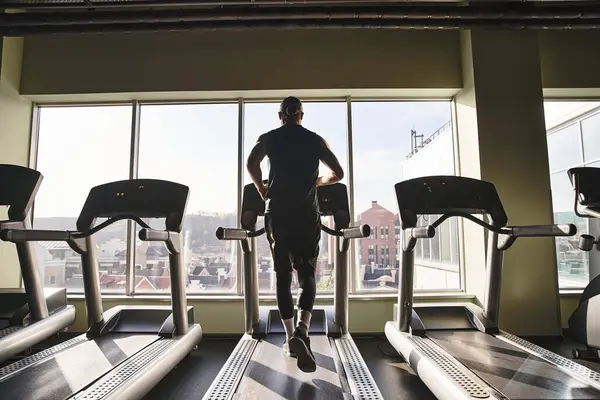 一个穿着运动服的健康男人在健身房的跑步机上跑步 把精力和精力投入到他的日常锻炼中 — 图库照片