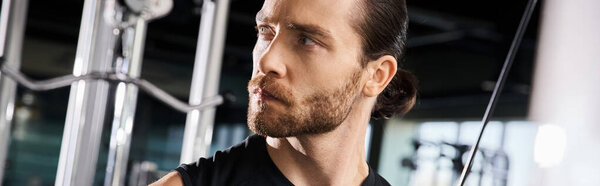 Атлетик в черной майке раздвигает границы, когда тренируется в спортзале..