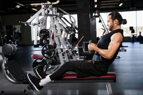 Aktif giyinen atletik bir adam spor salonunda tek başına oturur ve antrenmanının ortasında bir an durup düşünür..