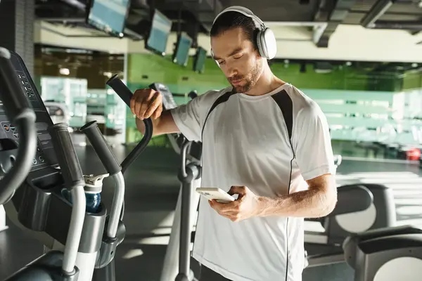 Focused Man Athletic Wear Wearing Headphones Using Cell Phone While — Stock Photo, Image