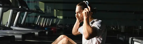 Stock image A man in active wear sits on a mat, engrossed in his music