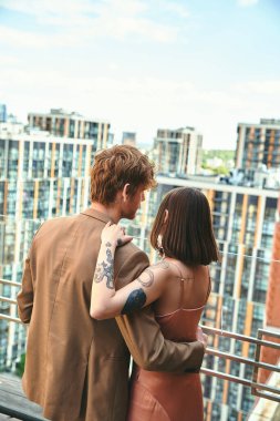 Bir adam ve bir kadın birlikte bir balkonda, manzaranın tadını çıkarıyorlar ve huzurlu bir öğleden sonra birbirlerine eşlik ediyorlar.